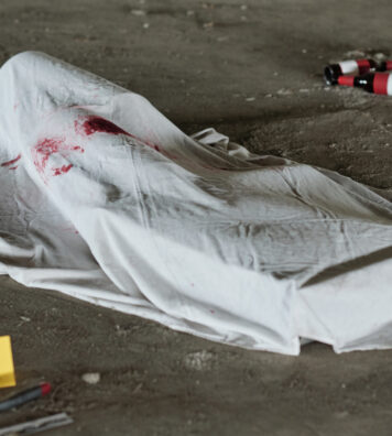 White sheet with stains of blood covering dead body shot with handgun or killed by knife or some other murder weapon